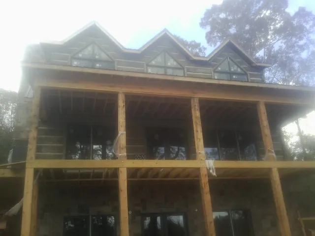 Dormers and porch framing on a large log home under construction — Roof Coating work by our crew in Willington