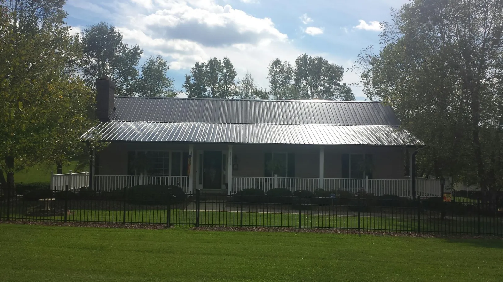 Gray metal roof on a brick ranch with a full width front porch — Gutter Guard Installation work by our crew in Willington