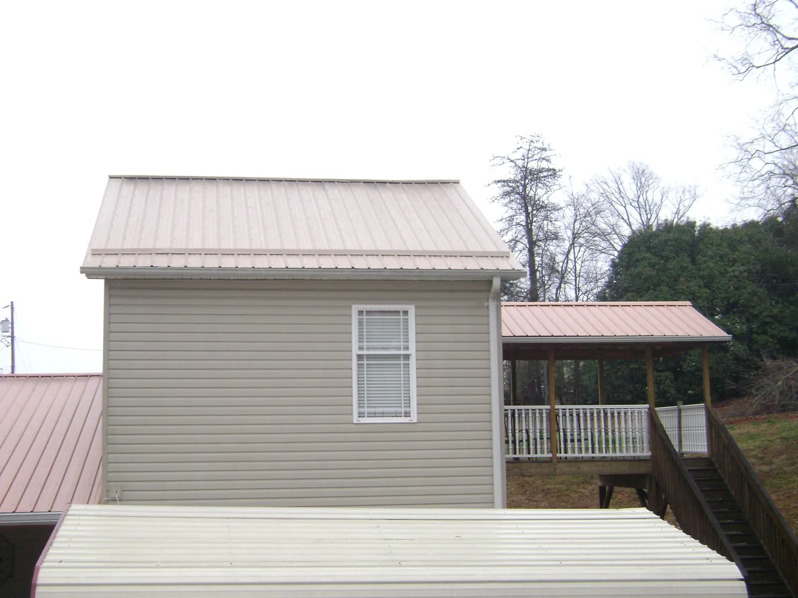 Tan metal roofs on a two story addition and attached porch, from a Roof Replacement job in Willington