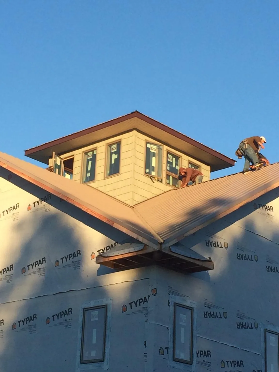 Roofers working around a rooftop cupola on a new metal roof at sunset — Roof Waterproofing in Willington by Roofing Brothers